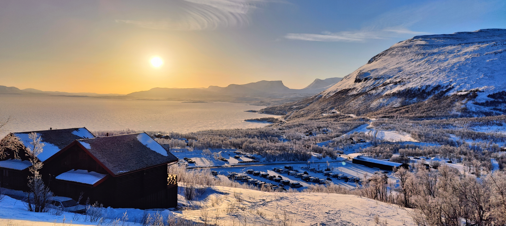 Golden sunset over a frozen Nordic valley with a lone cabin